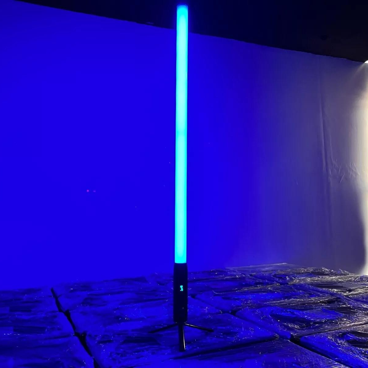It features 192 RGBWA LEDs for full-color 360° illumination, with an IP65-rated aluminum housing, 9600mAh battery, wireless DMX control, and OLED display for versatile outdoor lighting setups. About 1.5 meters (59" inches) tall. Resembles a lightsaber.
