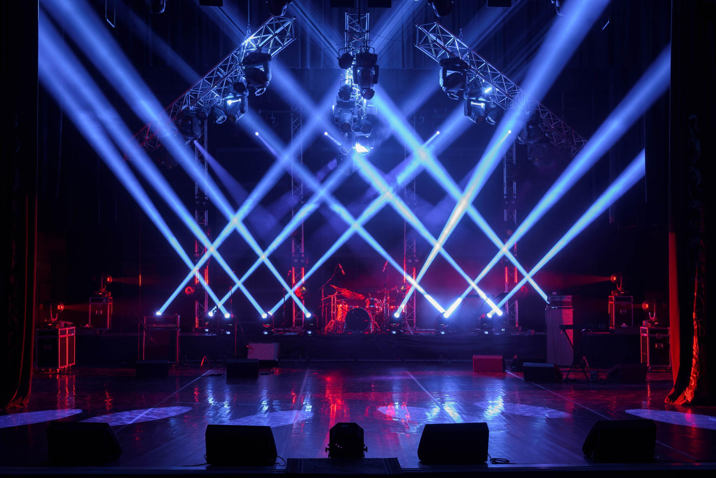 Stage LED Beams pointing up in criss cross pattern. Red RGBW at floor level.